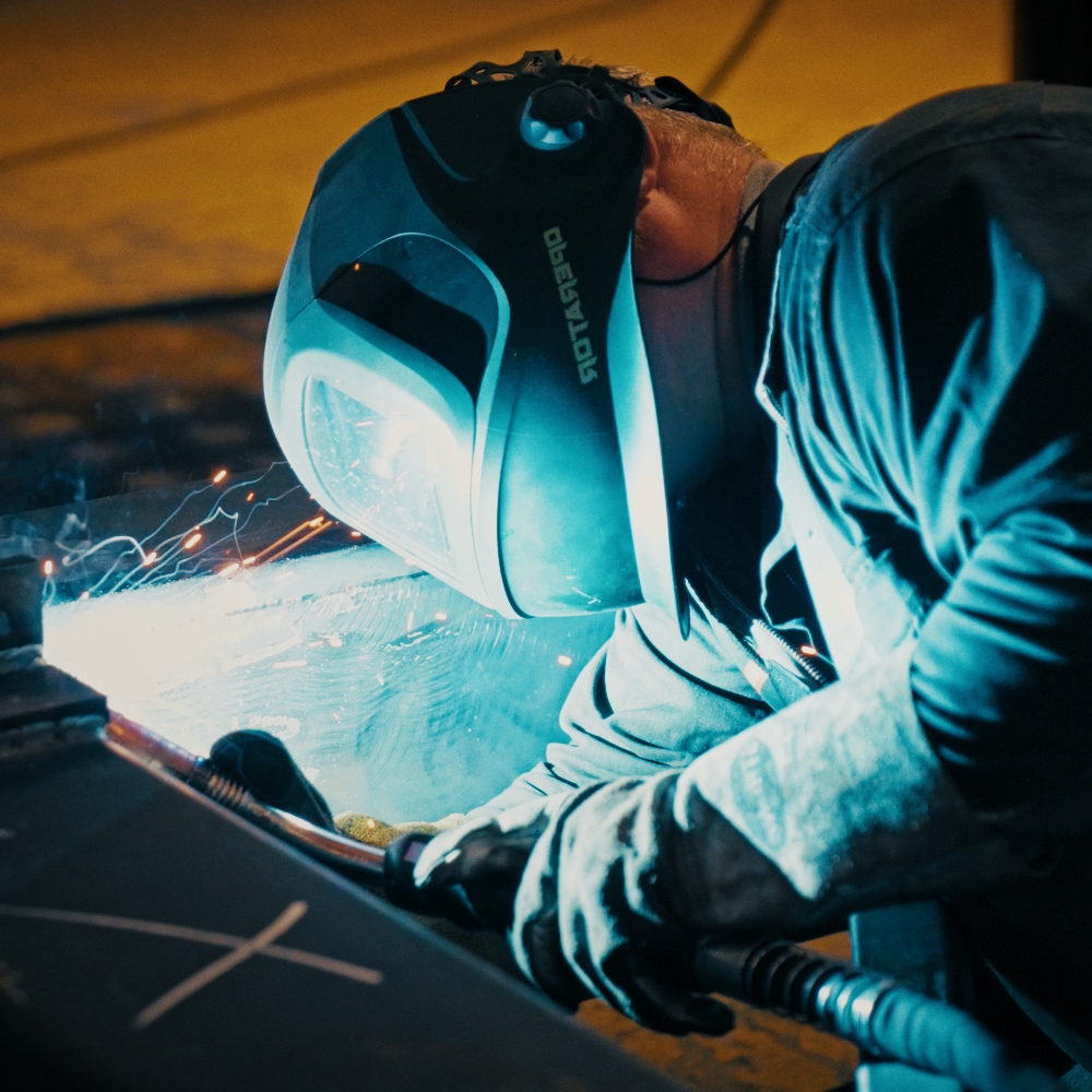 Schweißer mit Schutzhelm beim Arbeiten, Funkenflug während des Schweißprozesses bei MS Metalltechnik Schießl GmbH